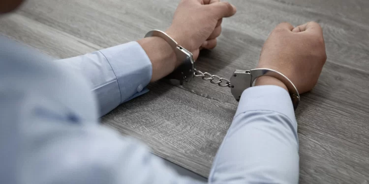 selective-focus-shot-male-hands-handcuffs-wooden-table-1.webp